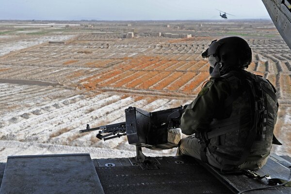 A soldier with a machine gun looking at the horizon