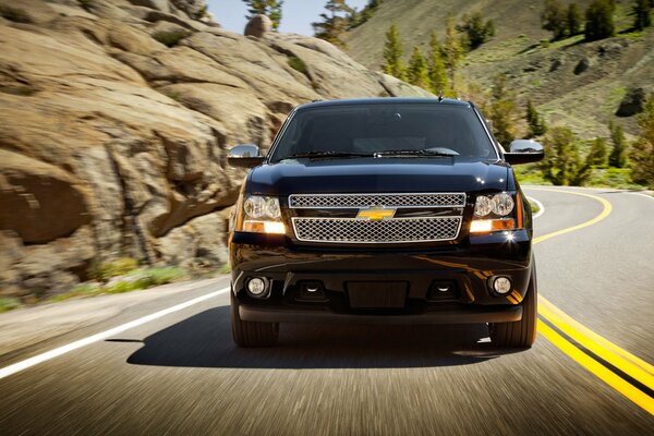 A 2013 chevrolet is driving along a suburban road