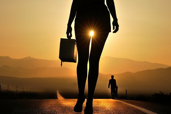 Silhouette of a girl with a suitcase at sunset