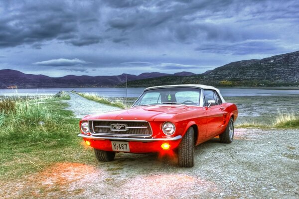 Red mustang by the lake in cloudy weather