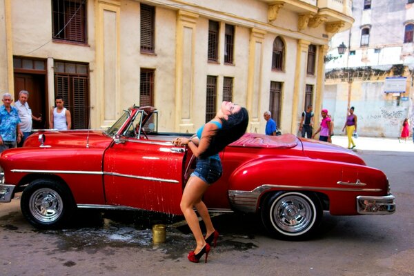 A red Chevrolet and a brunette girl next to it
