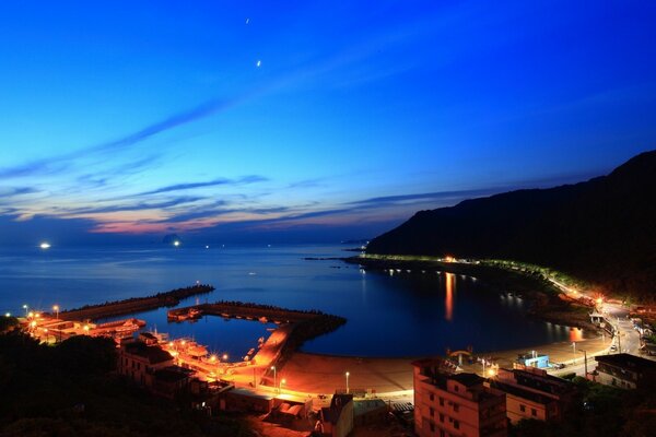 Night city by the sea. Sunset