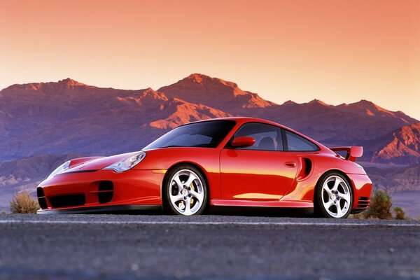 There is a beautiful red car on the background of the mountains