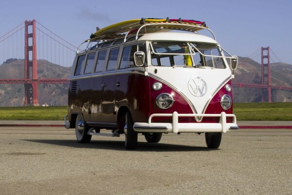 A red and white bus on the background of the famous Golden Gate Bridge. Cute bright Volkswagen bus