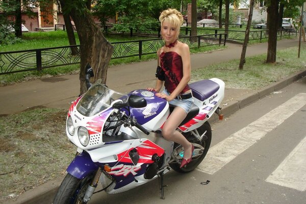 A woman in a miniskirt on a motorcycle on the road