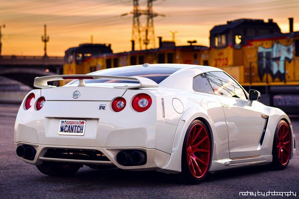 White Nissan car with red wheels