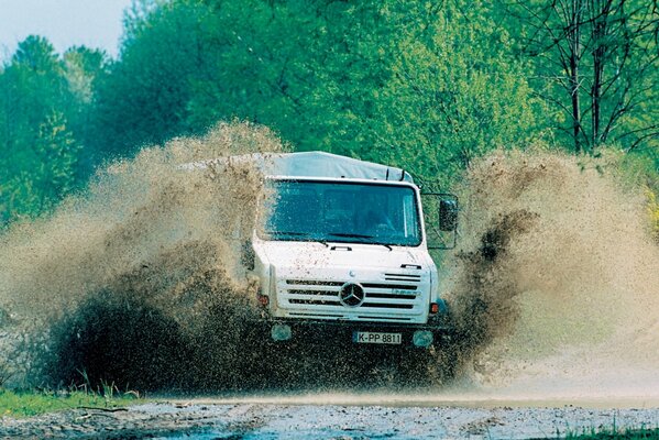The truck is driving at high speed through a puddle. splashes