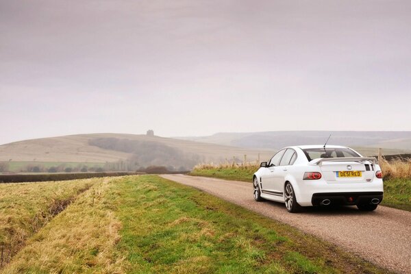 A white car with a spoiler in the field