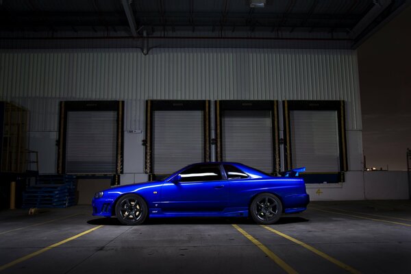 The Nissan r34 blue car is standing in the dark on the street