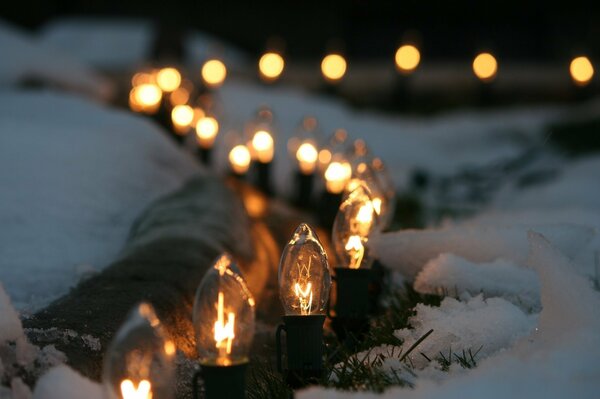 A chain of light bulbs on white snow