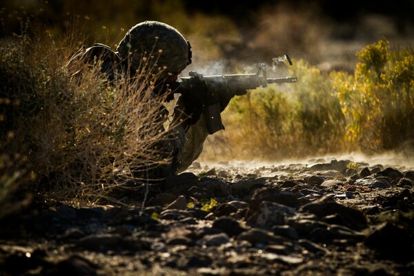 A soldier in a helmet shoots from a machine gun