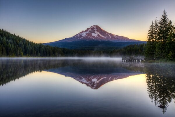 Forest and mountains are reflected in the water of the lake