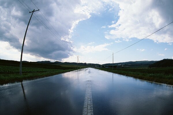 A road stretching to the horizon, with pillars on the sides and a sky with large clouds