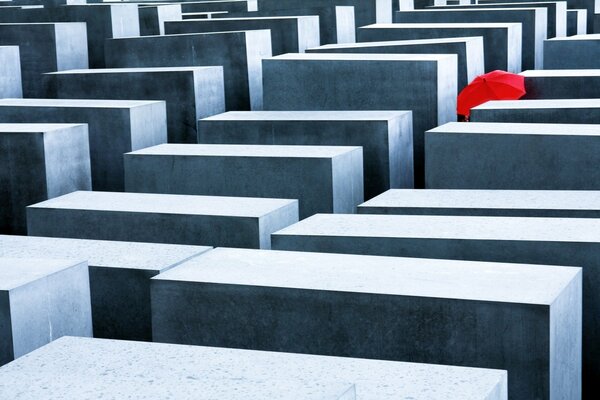 Lots of gray slabs and walls of different sizes, and a red umbrella next to one of them