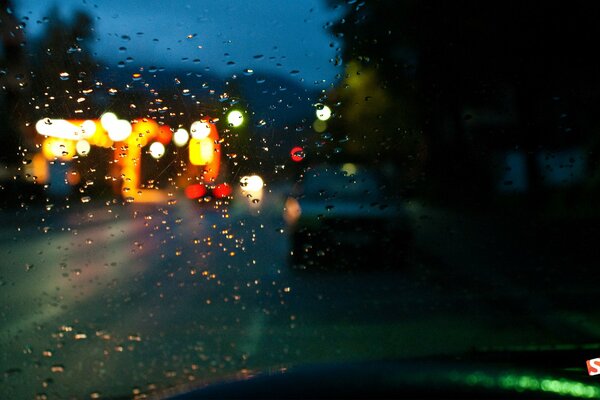 Rain on the street behind the windshield of the car