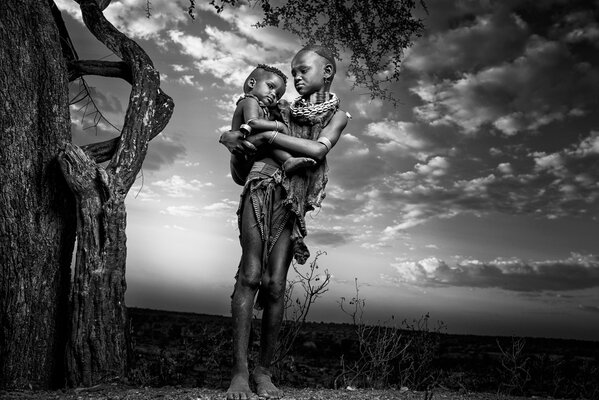 African mother with a baby next to a tree