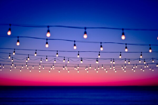 Lines of wires decorated with lamps on a sunset background