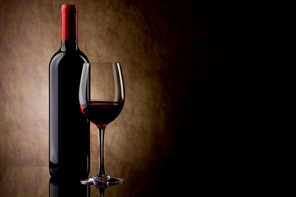 A bottle of red wine and a wine glass with wine