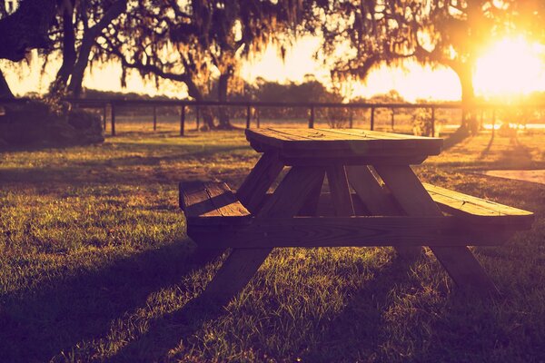 Wooden bench with a table on the background of sunset