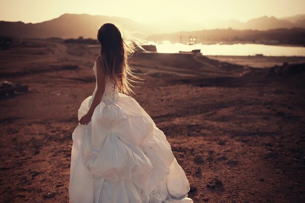 A girl in a white wedding dress on the background of a pond