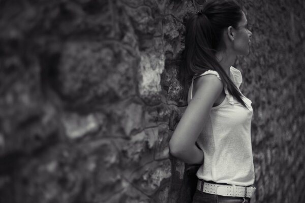 A brunette girl is standing near a gray wall