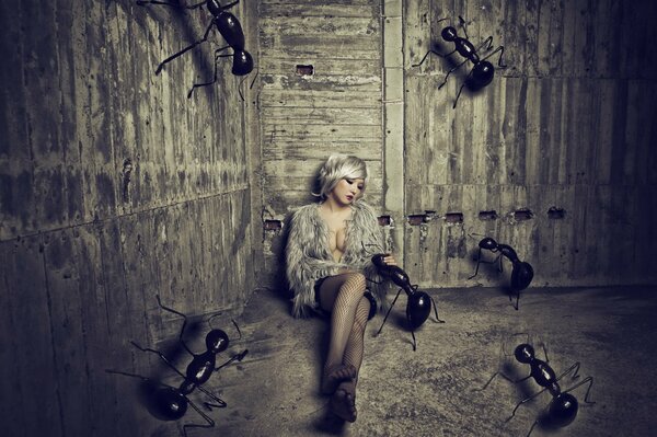 A girl sitting on the sand in a barn with huge ants