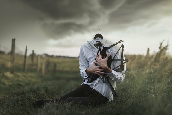 A man in the middle of a field with hangers in his hands