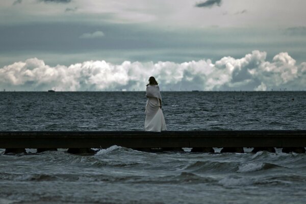 The girl looks at the raging sea
