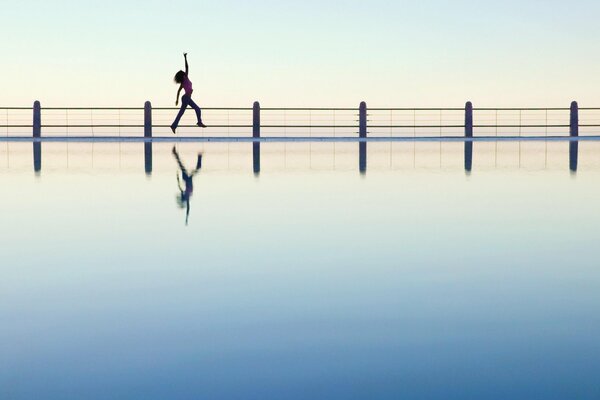 A girl bounces on a bridge in the distance
