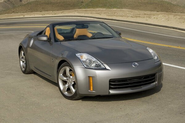 A silver Nissan car is on the road