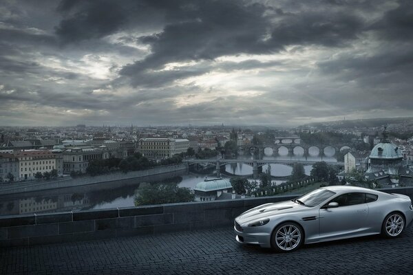 Aston Martin on the background of a city with clouds