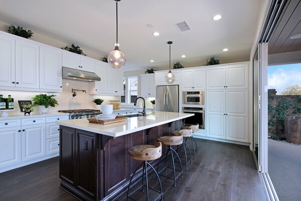 A bright kitchen with lamps above the table and a view of the street