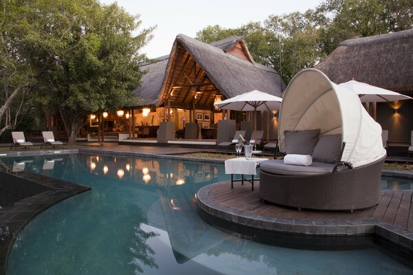 A house with a swimming pool, sun beds and a cozy sofa