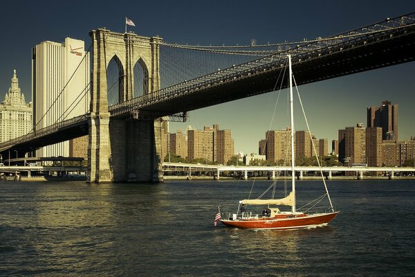 A yacht sailing under the Brooklyn Bridge