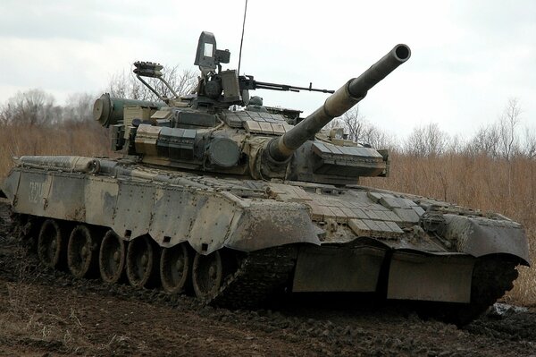 A military tank is driving on a muddy road