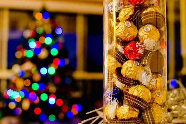 A jar of sweets in the foreground and a decorated Christmas tree in the back