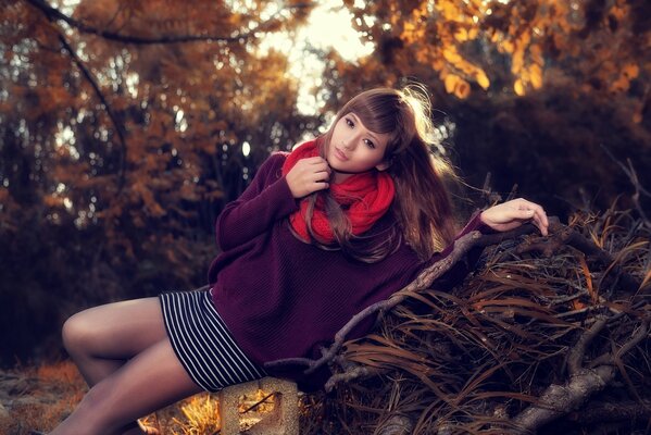 An Asian girl in a red scarf lies in the forest