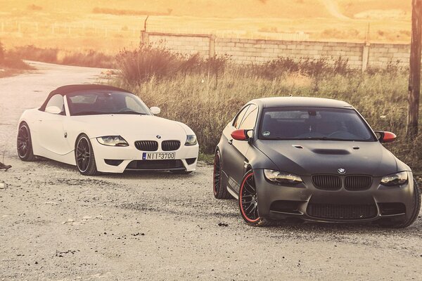 A white BMW overtakes a black one on the road
