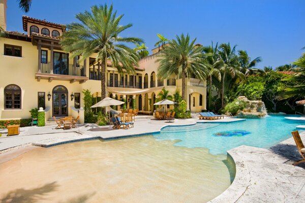 Tall palm trees stand in front of the villa by the pool
