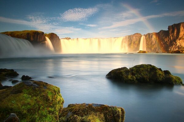 Rainbow on the background of a waterfall and moss