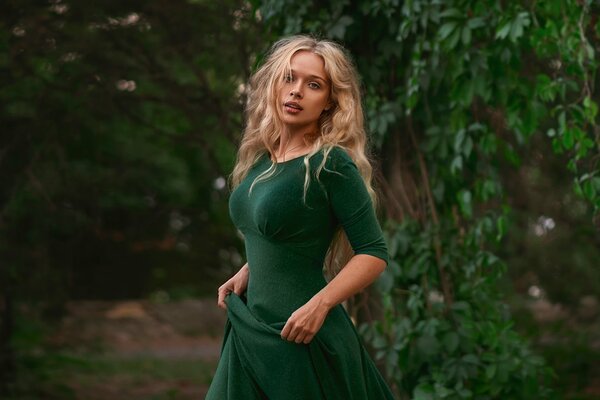 A girl in a green dress on a background of foliage