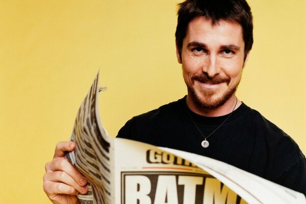 The man smiles and holds a magazine