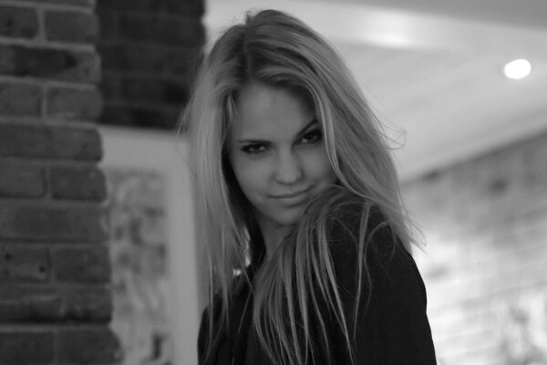 Black and white photo of model Emily Marie. In the photo, the girl sweetly squinted her eyes