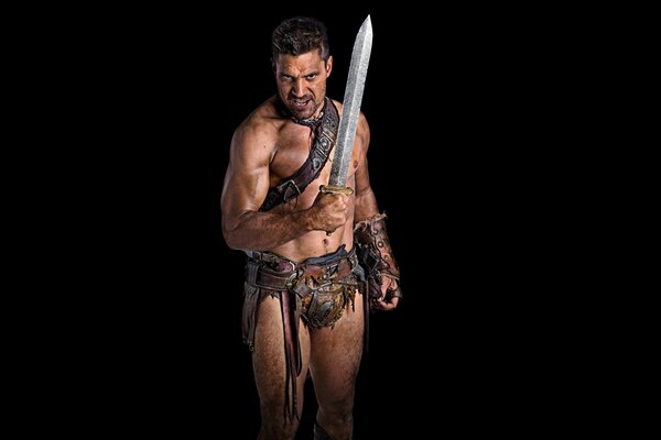 A handsome man stands with a sword