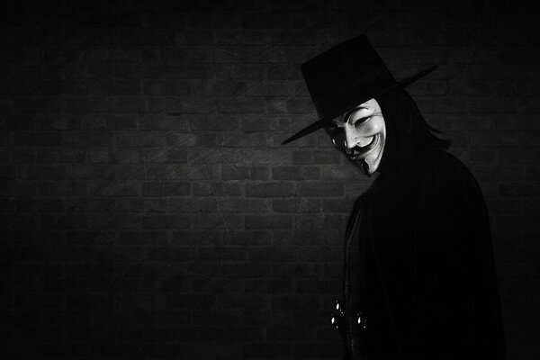 A masked man against a dark brick wall