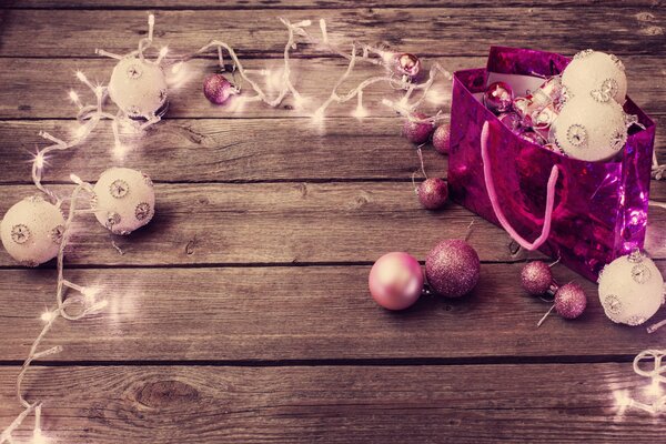 Pink Christmas garland with glowing balls on the wooden floor