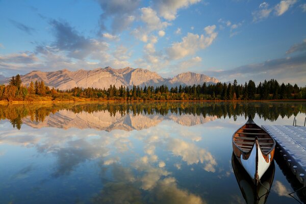 Boat at the pier in the lake against the background of the forest and the state with a cloudy sky
